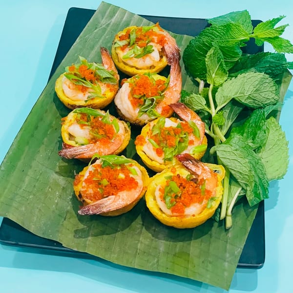 Vietnamese shrimp and pork mini pancakes with herbs and fish roe on a banana leaf.